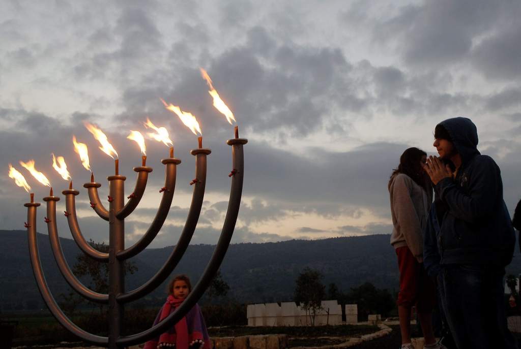 上图:光明节灯台(Hanukkah menorah)。主前168年,安提阿四世强制推行希腊化,在圣殿里竖起宙斯祭坛,用猪献祭,并强迫犹太人吃猪肉,导致了马加比起义。犹大马加比收复耶路撒冷以后,下令洁净圣殿,庆祝八天「修殿节」。当时人们在圣殿里只找到一罐有大祭司封印的用于点燃金灯台的灯油,无论是制作还是去外地取来这种专门洁净过的灯油,都需要八天时间。但这罐只能燃用一天的灯油,竟然一直燃烧了八天。为纪念此事,修殿节最主要的仪式是点燃九枝灯台,中间的灯盏用来点燃其它八支灯盏,每天多点一枝,一直到第八天,所以「修殿节」也被称为「光明节」。
