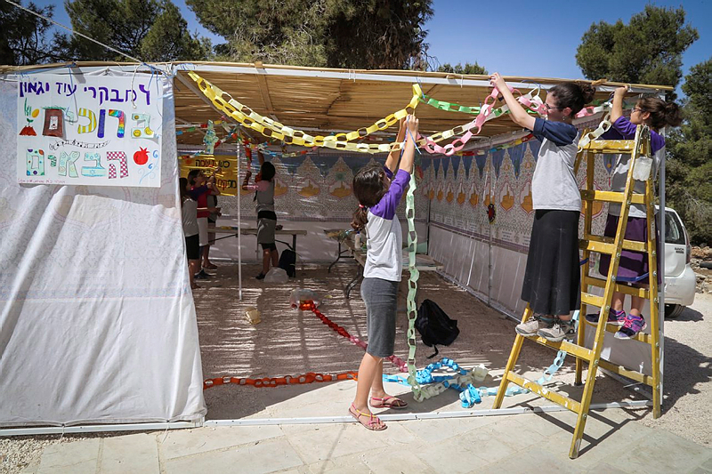 上图:几个犹太女孩正在装饰住棚节(Sukkot)的棚子。这棚子只有三面墙,通常用树枝和秋果来布置。犹太人被掳巴比伦回归之后,以斯拉吩咐各人用「橄榄树、野橄榄树、番石榴树、棕树和各样茂密树的枝子」在自己的房顶上、院内或城中宽阔处搭棚(尼八15-18)。住棚节犹太人还要在会堂诵读传道书。