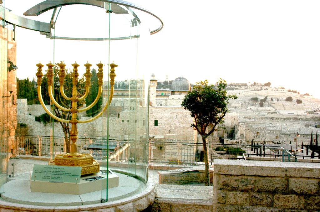 上图:从耶路撒冷圣殿研究所(The Temple Institute)门口的金灯台(Golden Menorah)俯瞰圣殿山的阿克萨清真寺(Al-Aqsa Mosque)。这个金灯台是圣殿研究所制造的,重500公斤,用了45公斤24K黄金,准备放到将来重建的第三圣殿里。目前,圣殿研究所已经完成了重建圣殿的大部分准备工作,剩下的最大难题就是殿址。因为第二圣殿的原址上建有伊斯兰教圣地岩石圆顶殿(Dome of the Rock),若要强行拆毁,后果不堪设想。圣殿研究所希望将岩石圆顶迁至另一个地点,而有些正统犹太人则认为第三圣殿只能在弥赛亚时代重建。目前,穆斯林拒绝承认岩石圆顶是第二圣殿的原址,并且不允许进行考古挖掘;而不少犹太人和考古学家则认为,第二圣殿的确切地址可能在岩石圆顶以北或以南一百米左右。还有犹太人认为,未来的先知可以指定在摩利亚山的任何地点重建圣殿。因此,殿址问题并非无解,在历史上,岩石圆顶曾于1015年地震中倒塌。将来若有新的考古发现、地震或形势的变化,两殿共存也并非没有可能。重建圣殿是末日大灾难和基督再来的前兆,「一七之内,他必与许多人坚定盟约」(但九27),很可能是预言在敌基督的安排之下,以色列与伊斯兰世界达成了和平协议,圣殿得以重建。