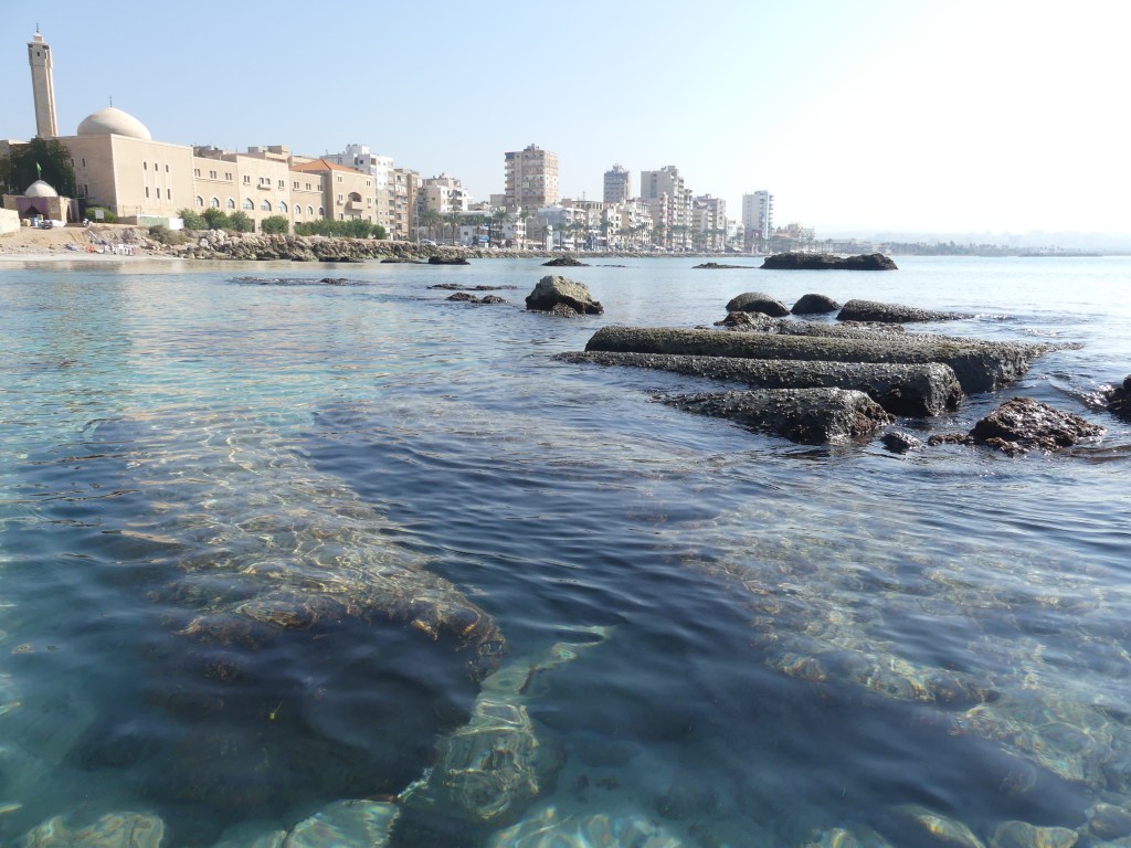 上图：沉没在地中海里的古代推罗城的柱子，背景是陆上的现代推罗城。今天，推罗是黎巴嫩的第四大城市，仅次于贝鲁特、的黎波里和西顿。