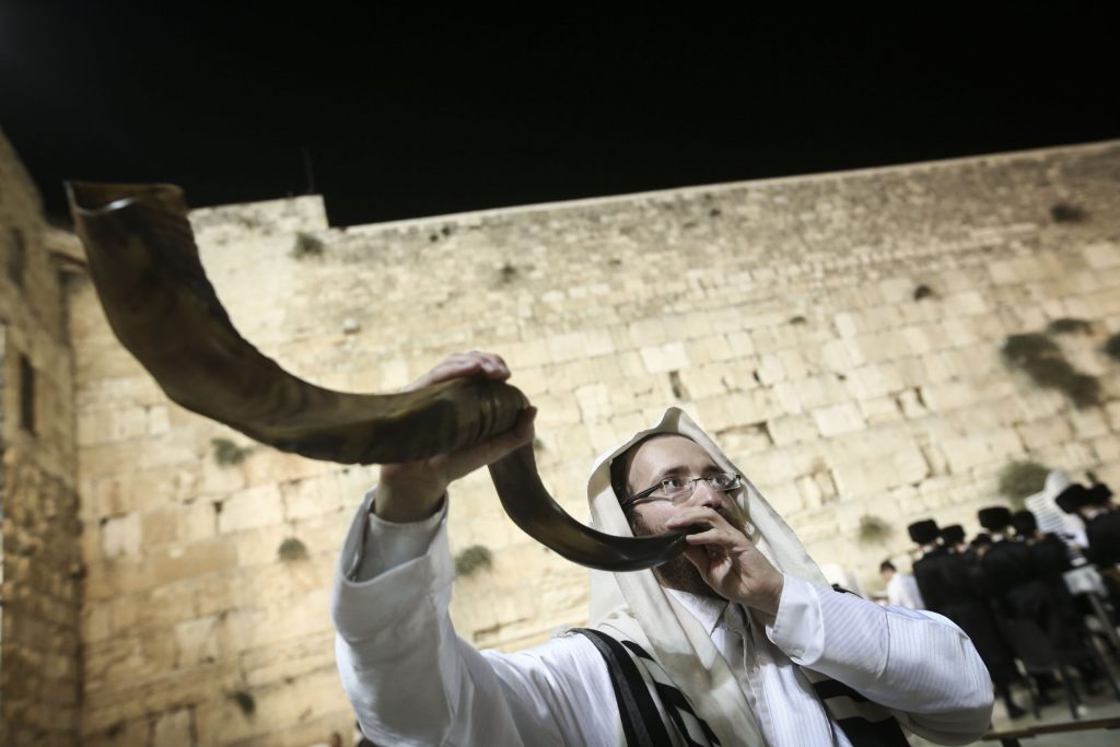 上图:一个犹太人于赎罪日在哭墙吹响羊角号(Shofar)。